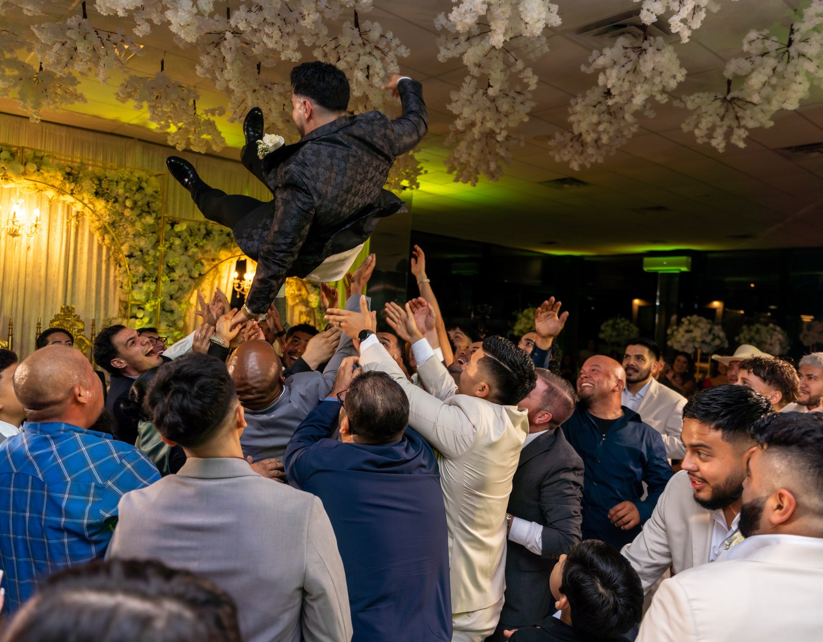Groom tossed in the air at wedding celebration