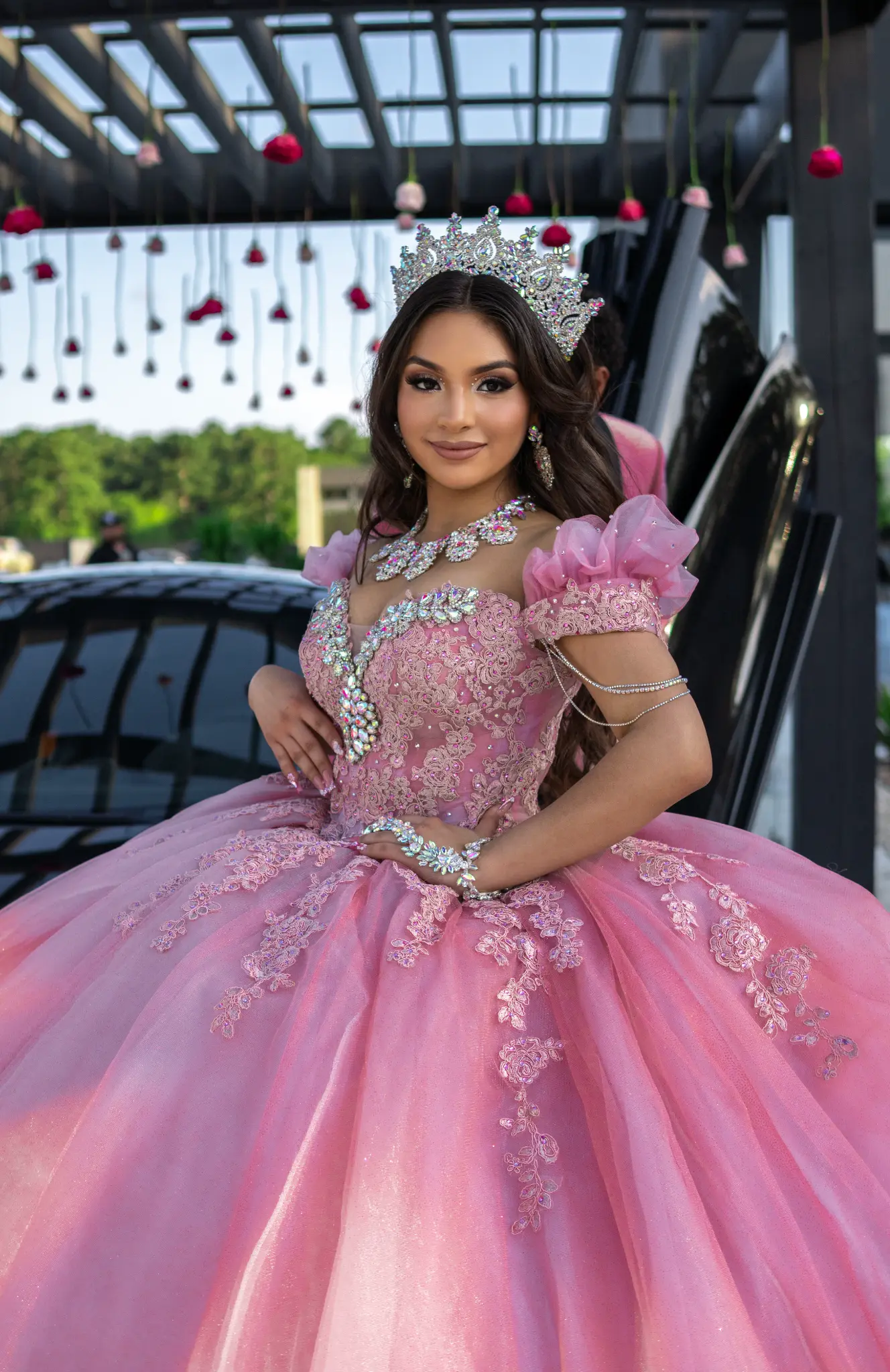Quinceañera in pink gown under rose pergola