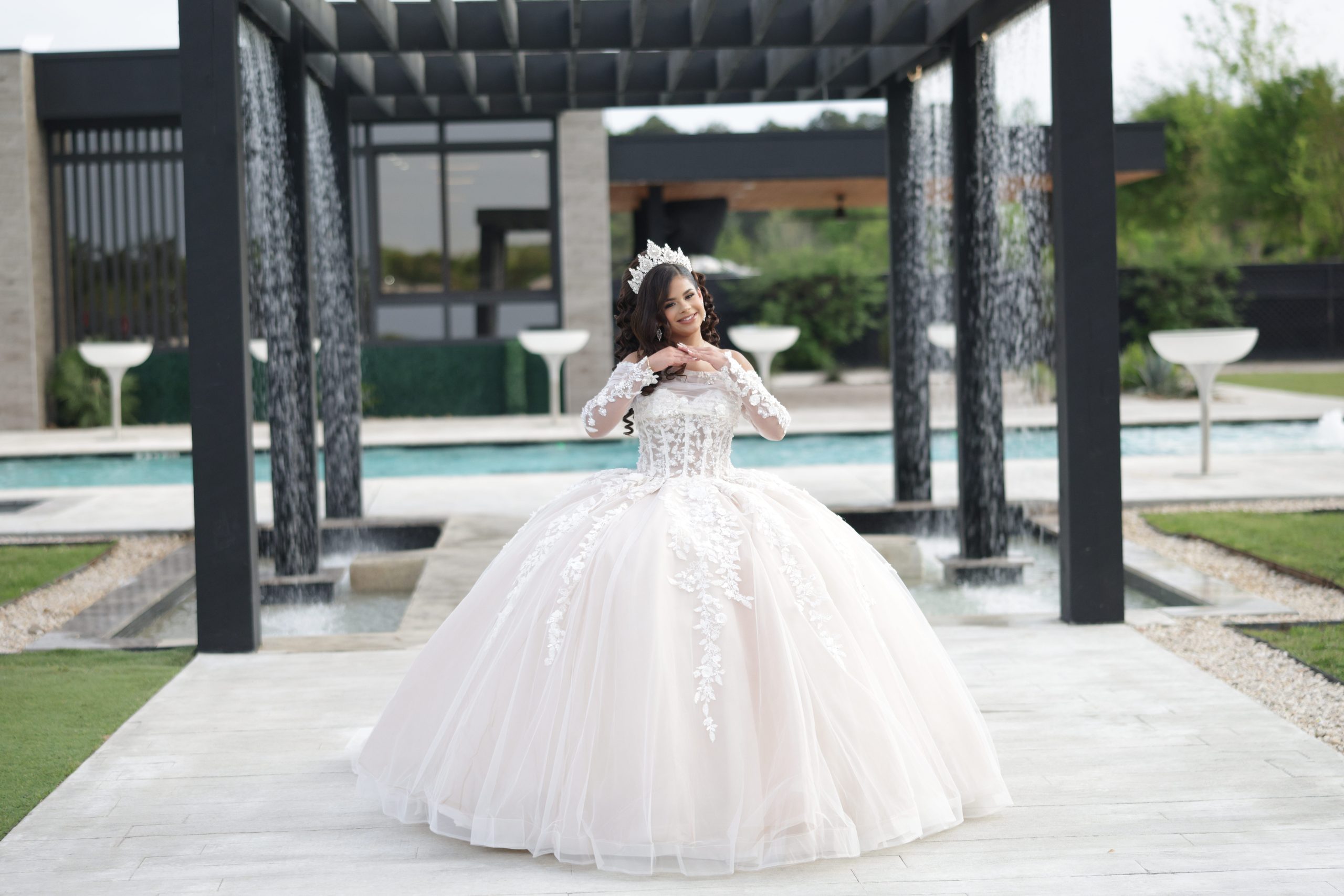 Quinceañera honoree in a white ball gown near the outdoor pergola and water feature at AG Outdoor Venue